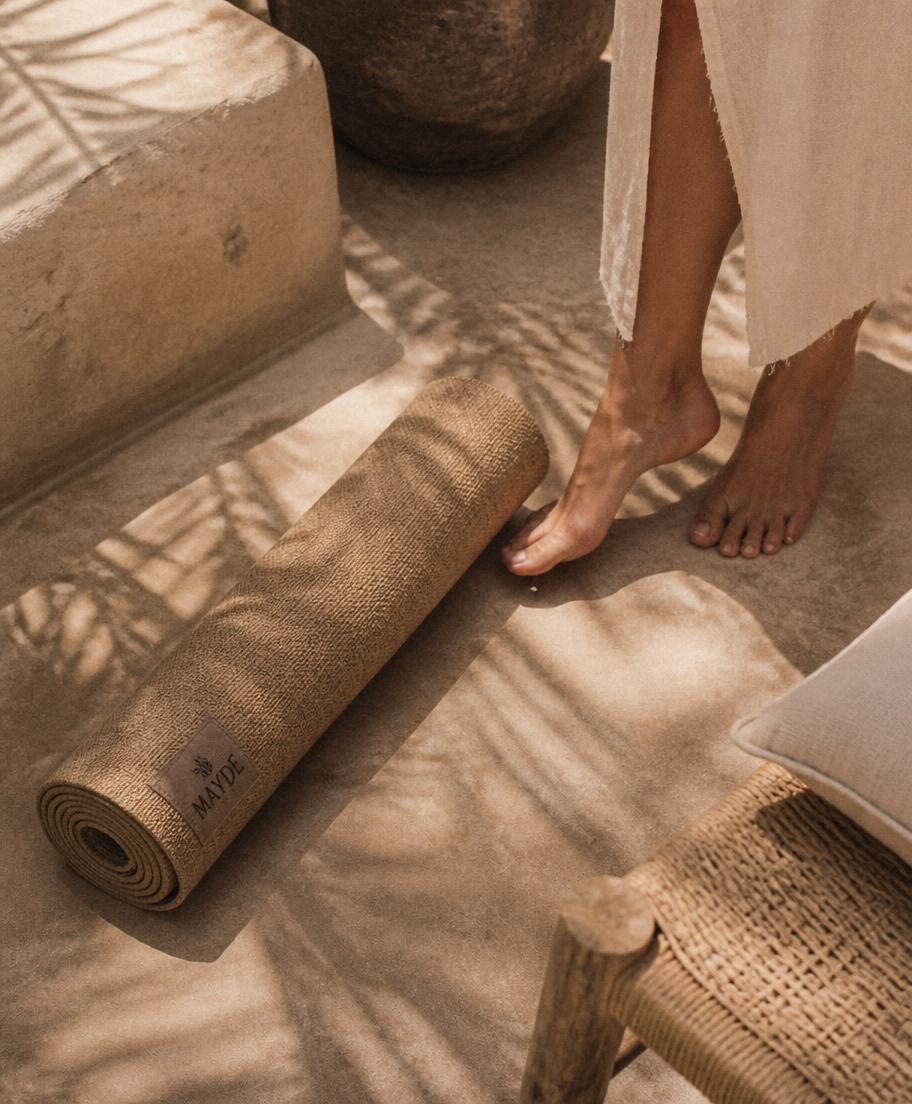 Natural jute Pilates mat on warm sandstone with palm shadows